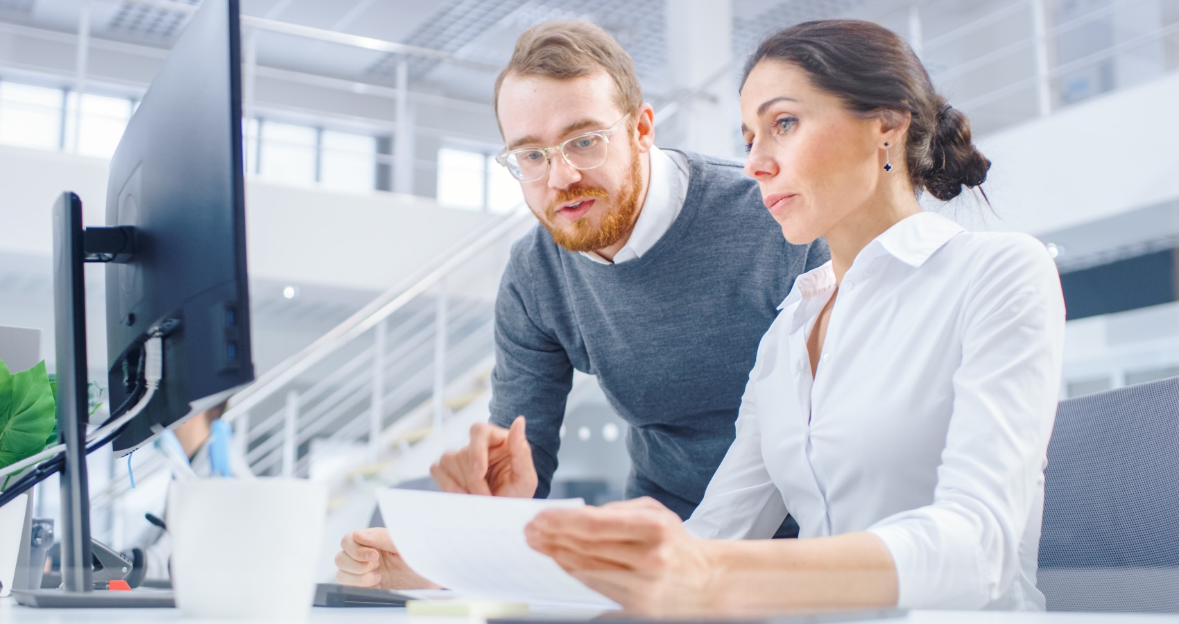 Businesswoman working at desk project manager standing beside